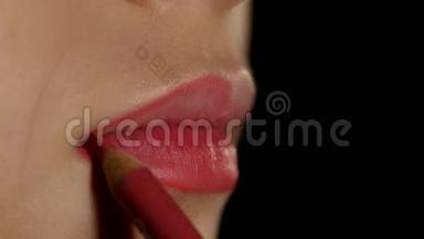 化妆师应用唇衬来模拟嘴唇。 黑色的。 特写